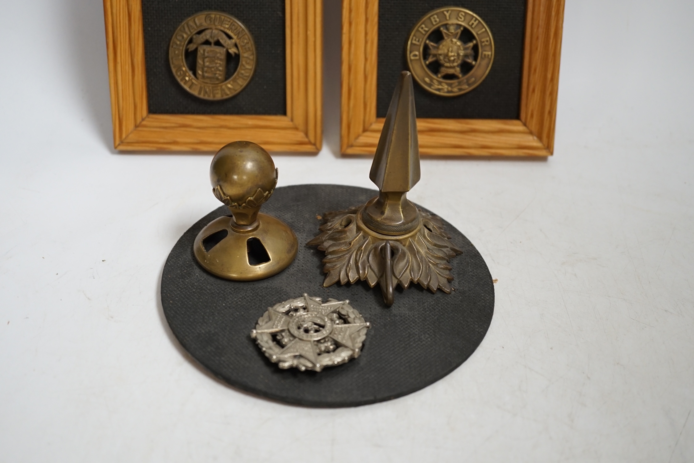 Six military helmet plates mounted on two boards, together with two helmet spikes and a cap badge, including; the Yorkshire Regiment, the Royal Guernsey Light Infantry, the Loyal North Lancashire, the Lincolnshire Regime
